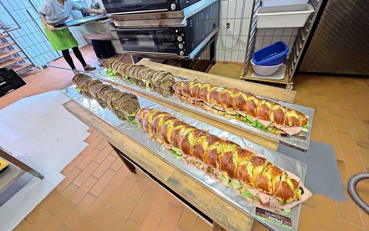 Die meterlangen Sandwich-Brote, einmal mit Laugenteig, einmal rustikal mit Körnern bestreut, sind belegt mit Fleisch, Käse, Salat, Tomaten und Gurken.
