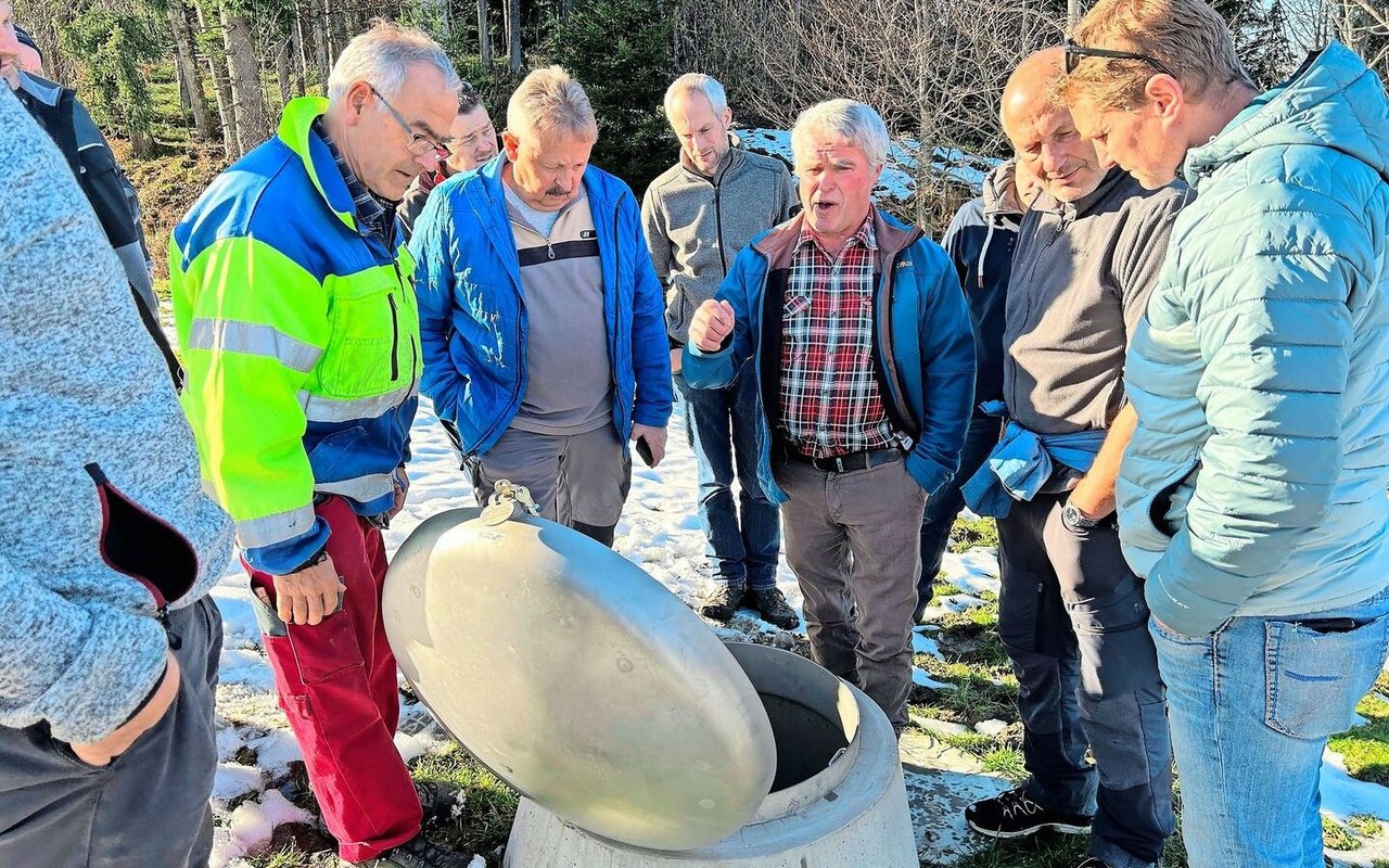 Die Teilnehmer stehen im Unteren Gäbris um die Brunnenstube, die erst kürzlich installiert wurde. Johannes Bodenmann (3. v. r.) weist auf die Vorteile der Chromstahlabdeckung hin. Sie sorgt dafür, dass das Oberflächenwasser nicht in die Brunnenstube fliesst. 