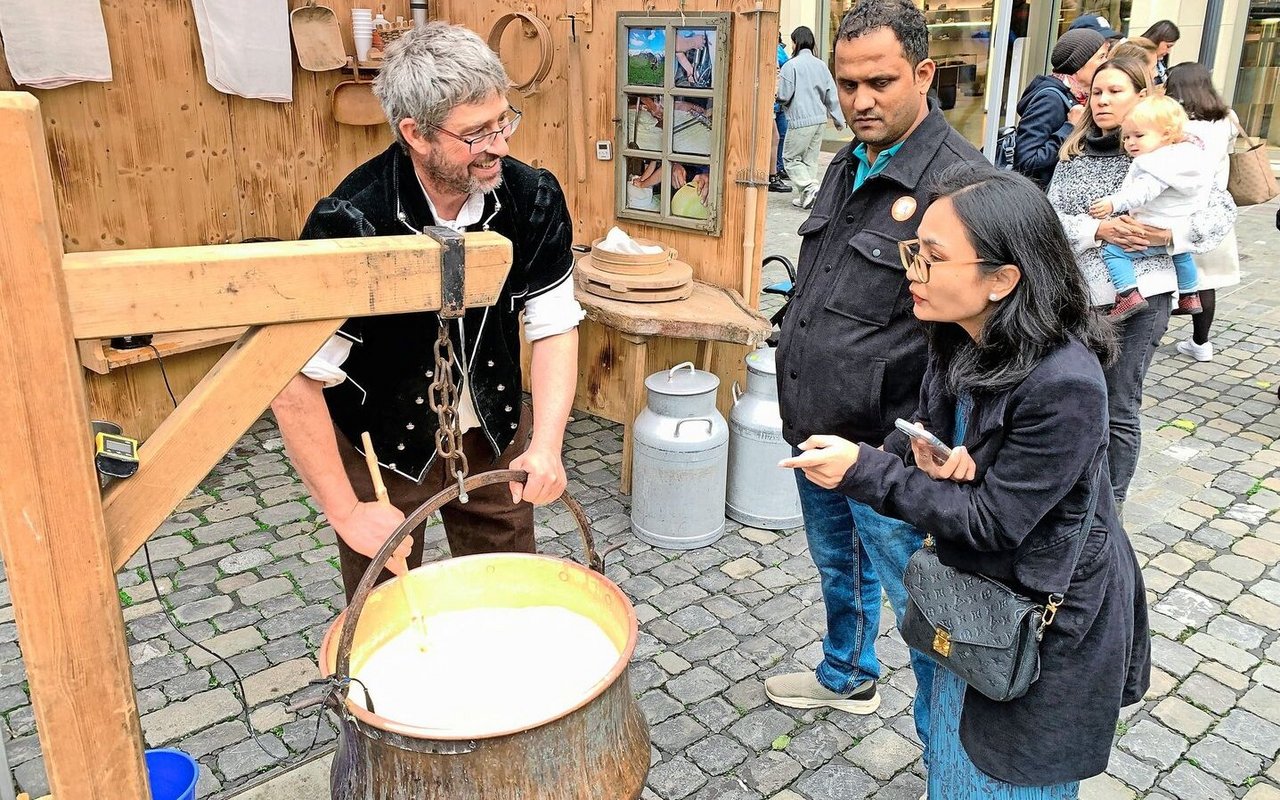 Landwirt Stefan Sieber aus dem Berner Oberland (l.) erklärt Touristen in Luzern die Herstellung von Käse. 