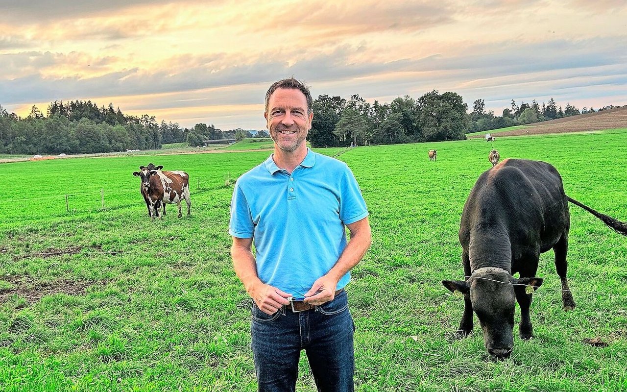 Hinter Daniel Nyfeler ist die Weide mit Stier Ando zu sehen. Der Stier sorgt für Fruchtbarkeit in den heissen Sommermonaten.